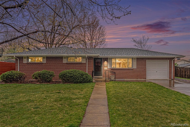 ranch-style home with fence, a front yard, brick siding, an attached garage, and driveway