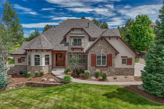 9121 Sunshine Meadow Pl, Parker, CO 80134 - french country home featuring stone siding, stucco siding, a front lawn, a balcony, and roof with shingles