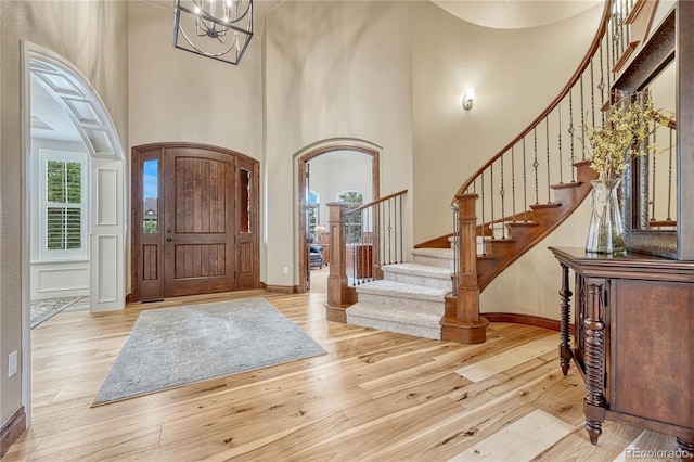 9121 Sunshine Meadow Pl, Parker, CO 80134 - foyer entrance with arched walkways, a high ceiling, wood finished floors, stairway, and baseboards