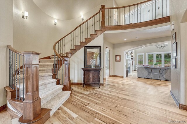 9121 Sunshine Meadow Pl, Parker, CO 80134 - foyer with arched walkways, hardwood / wood-style floors, a towering ceiling, stairs, and baseboards