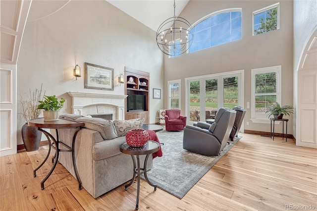 9121 Sunshine Meadow Pl, Parker, CO 80134 - living room with a towering ceiling, a chandelier, a fireplace, light wood-style flooring, and baseboards