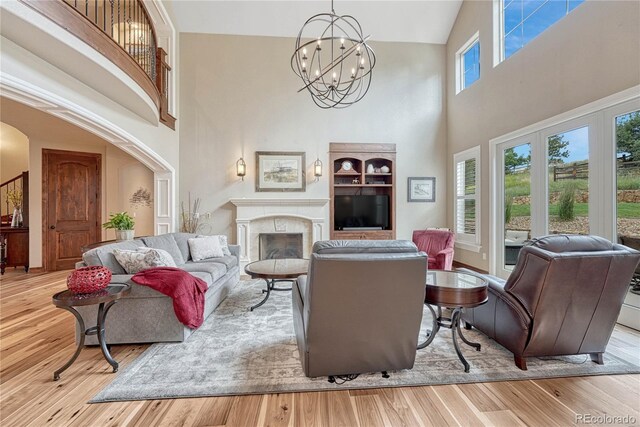 9121 Sunshine Meadow Pl, Parker, CO 80134 - living area featuring high vaulted ceiling, a chandelier, wood finished floors, a fireplace, and arched walkways