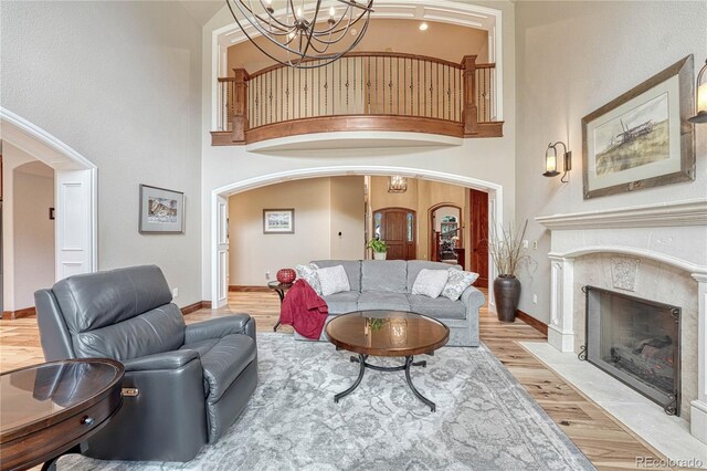 9121 Sunshine Meadow Pl, Parker, CO 80134 - living area featuring arched walkways, light wood finished floors, a chandelier, baseboards, and a towering ceiling