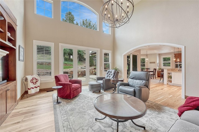 9121 Sunshine Meadow Pl, Parker, CO 80134 - living room with a high ceiling, light wood finished floors, arched walkways, a chandelier, and healthy amount of natural light