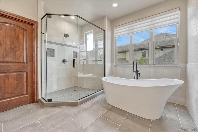 9121 Sunshine Meadow Pl, Parker, CO 80134 - bathroom with a freestanding bath, a shower stall, tile walls, tile patterned floors, and wainscoting