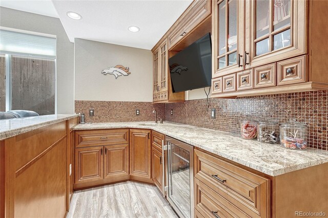 9121 Sunshine Meadow Pl, Parker, CO 80134 - kitchen with wine cooler, light stone counters, a sink, decorative backsplash, and glass insert cabinets