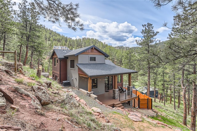 795 Pine Brook Rd, Boulder, CO 80304 - view of front of house with a shingled roof, a view of trees, central AC unit, covered porch, and stucco siding