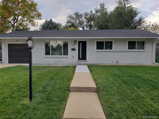 ranch-style home featuring a shingled roof, a front yard, brick siding, and an attached garage