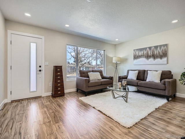 living room with a textured ceiling, baseboards, wood finished floors, and recessed lighting