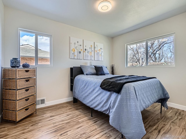 bedroom featuring wood finished floors, visible vents, and baseboards