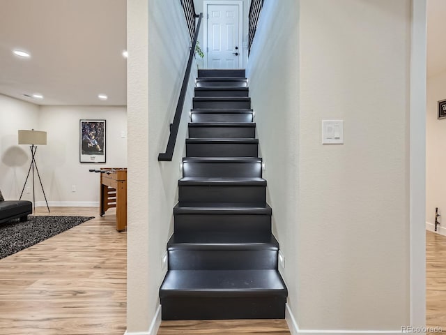 staircase with baseboards, wood finished floors, and recessed lighting