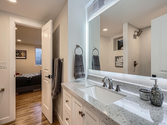 bathroom featuring vanity, wood finished floors, visible vents, and connected bathroom