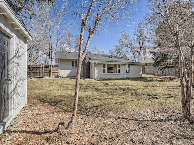 exterior space with brick siding, a yard, and a fenced backyard