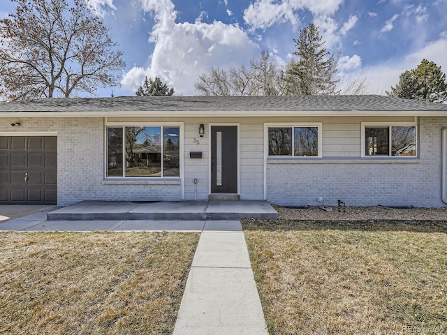 ranch-style home with brick siding, a front lawn, and a shingled roof