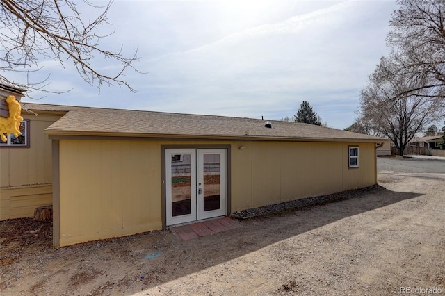 back of property featuring french doors and a shingled roof