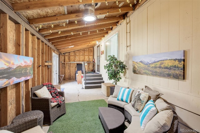 living area featuring lofted ceiling, stairway, and wooden walls