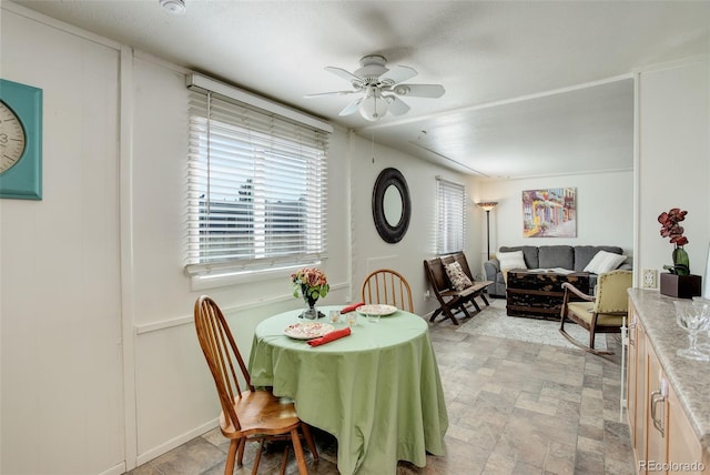 dining space with stone finish floor and ceiling fan