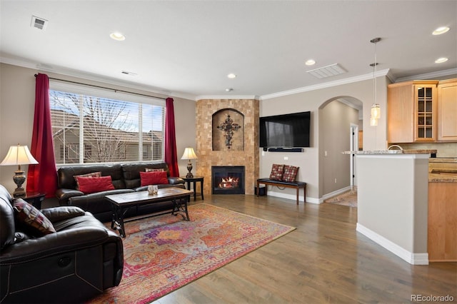10127 Bluffmont Ln, Lone Tree, CO 80124 - living area with arched walkways, crown molding, wood finished floors, a large fireplace, and recessed lighting