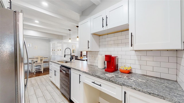 3067 S Holly Pl, Denver, CO 80222 - kitchen featuring appliances with stainless steel finishes, a sink, decorative backsplash, white cabinets, and light stone countertops