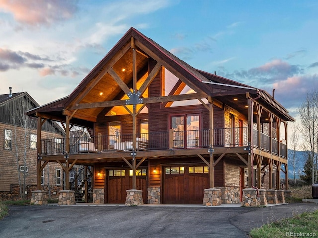 152 Bergamot Dr, Tabernash, CO 80478 - view of front of house featuring stone siding, driveway, a balcony, a garage, and stairway