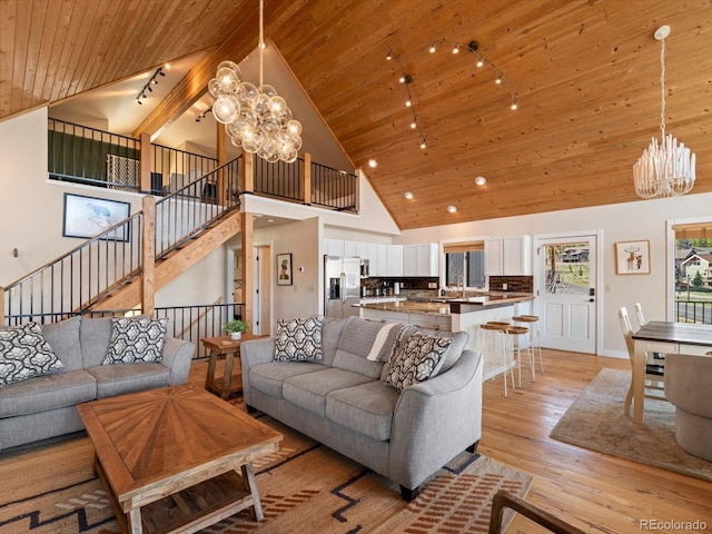 152 Bergamot Dr, Tabernash, CO 80478 - living area featuring a chandelier, wooden ceiling, light wood-style floors, high vaulted ceiling, and stairs