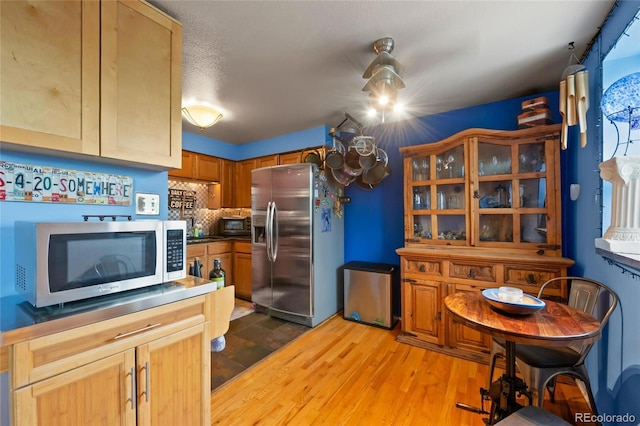 kitchen with a textured ceiling, stainless steel appliances, and hardwood / wood-style flooring