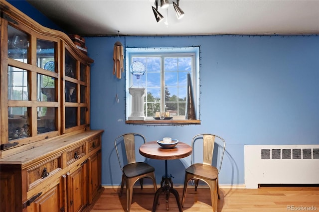 dining area with light wood-type flooring and radiator heating unit