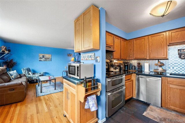 kitchen featuring decorative backsplash, appliances with stainless steel finishes, sink, and wood-type flooring