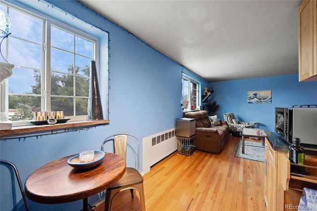 living room featuring a wealth of natural light, radiator heating unit, and light hardwood / wood-style flooring