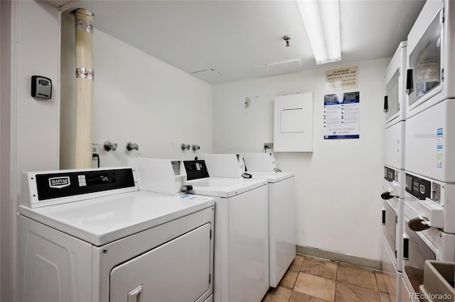 laundry room with stacked washing maching and dryer, washing machine and dryer, and light tile patterned flooring