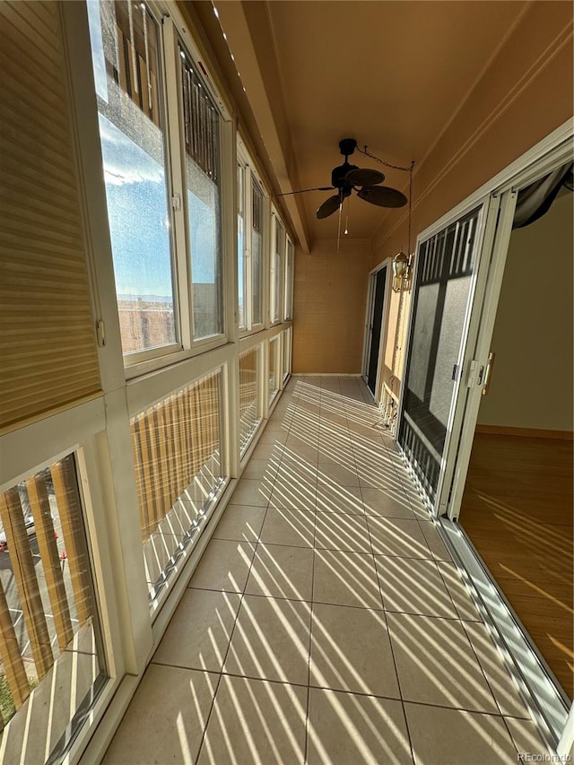 unfurnished sunroom with ceiling fan with notable chandelier