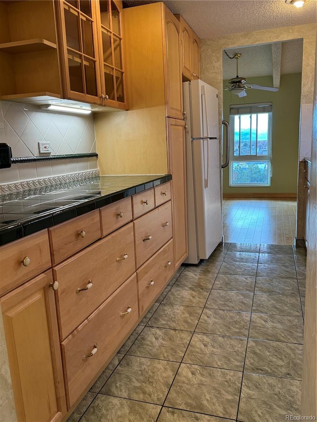 kitchen with backsplash, tile countertops, white fridge, wood-type flooring, and a textured ceiling