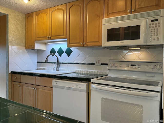 kitchen with sink, tile countertops, a textured ceiling, white appliances, and decorative backsplash