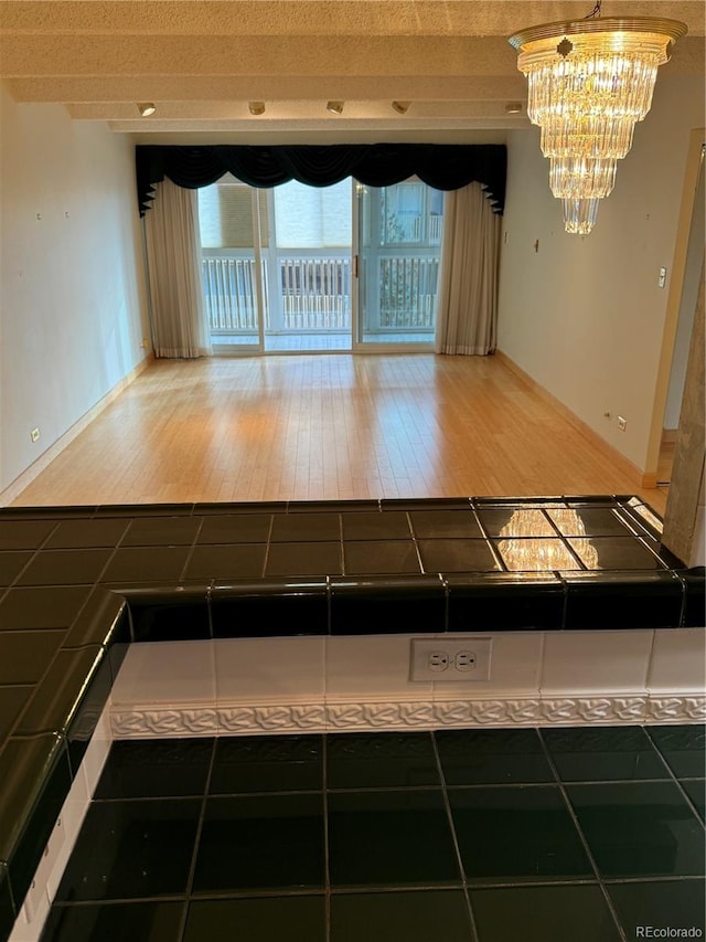 interior space featuring hardwood / wood-style floors, tile countertops, and a notable chandelier