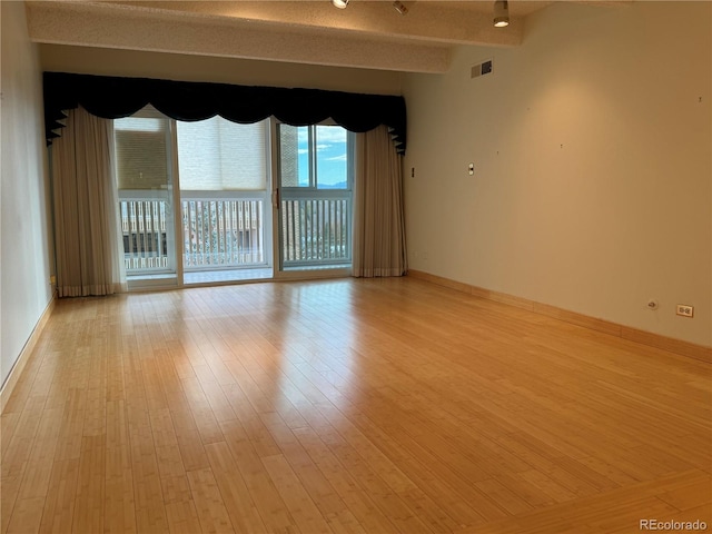 empty room with vaulted ceiling with beams and light hardwood / wood-style flooring