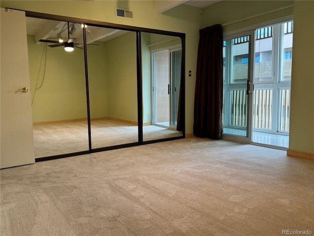 unfurnished bedroom featuring a closet, beamed ceiling, and light colored carpet