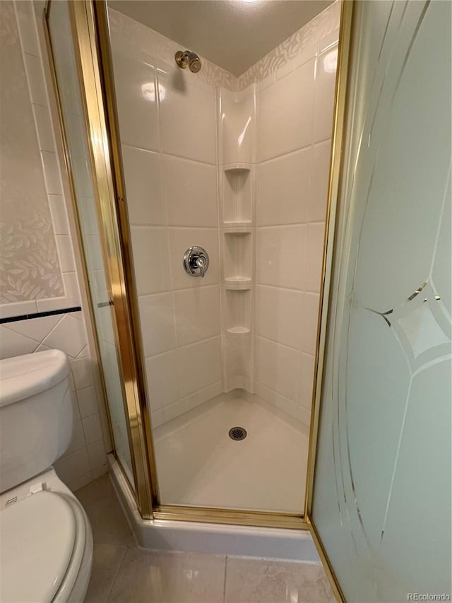 bathroom featuring tile patterned flooring, an enclosed shower, tile walls, and toilet