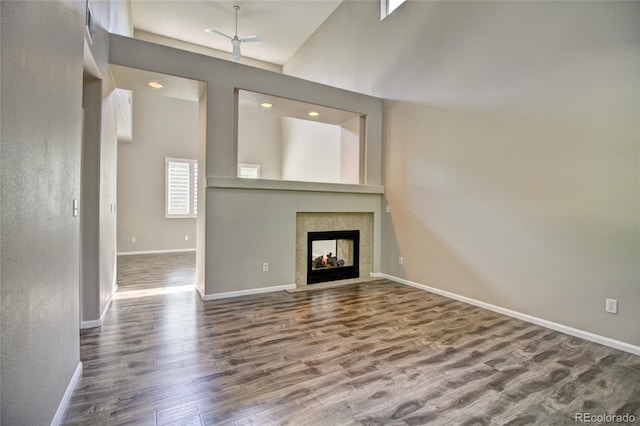 8416 S Reed St, Littleton, CO 80128 - unfurnished living room with dark wood finished floors, a tiled fireplace, baseboards, a towering ceiling, and recessed lighting