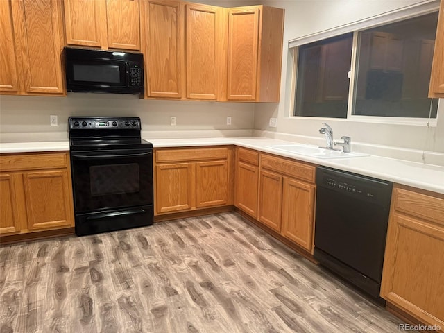 8416 S Reed St, Littleton, CO 80128 - kitchen with black appliances, a sink, light countertops, and light wood finished floors