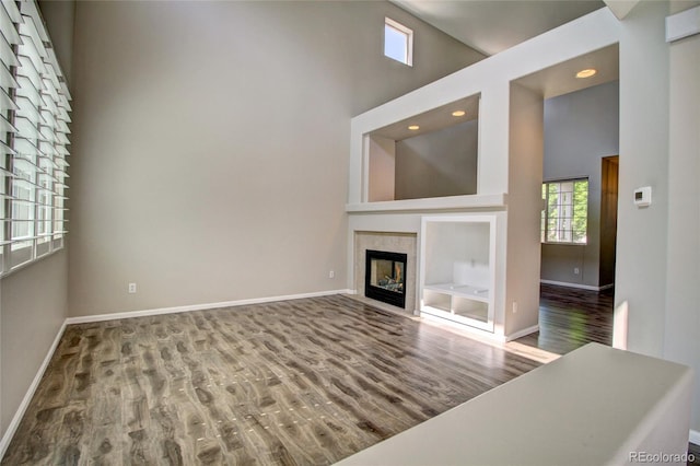 8416 S Reed St, Littleton, CO 80128 - unfurnished living room featuring a towering ceiling, wood finished floors, baseboards, a tiled fireplace, and recessed lighting