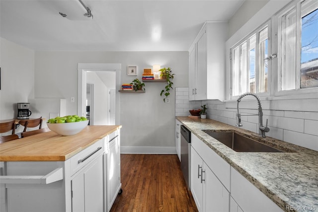 kitchen with sink, white cabinets, backsplash, stainless steel dishwasher, and light stone countertops