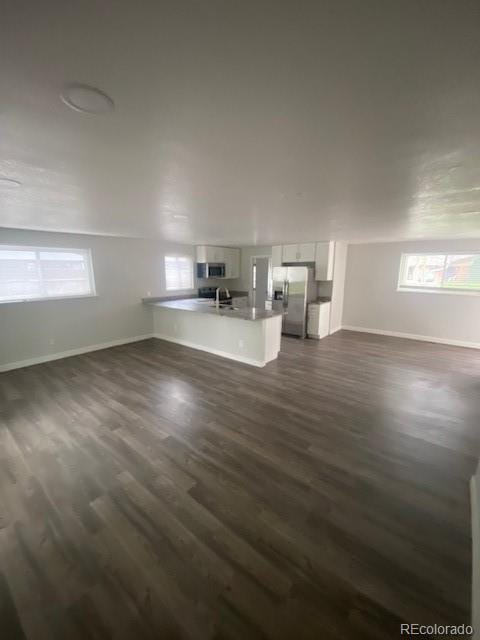 8220 E 104th Way, Henderson, CO 80640 - unfurnished living room featuring baseboards, dark wood-type flooring, and a sink