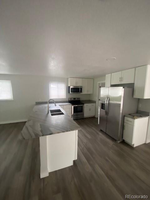 8220 E 104th Way, Henderson, CO 80640 - kitchen featuring stainless steel appliances, a sink, white cabinets, a peninsula, and dark wood-style floors