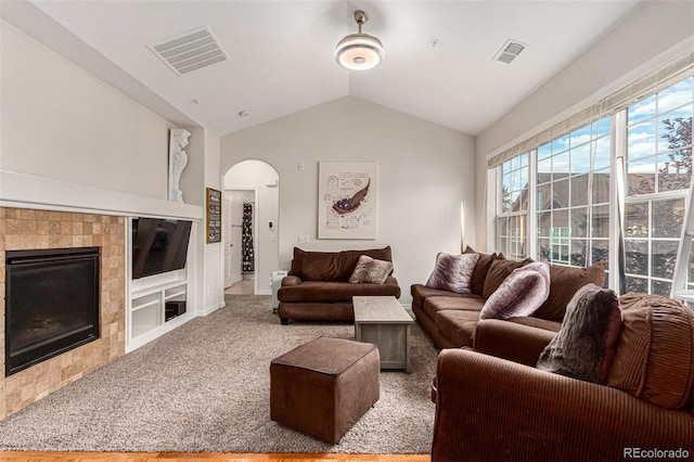 carpeted living room featuring lofted ceiling and a tiled fireplace