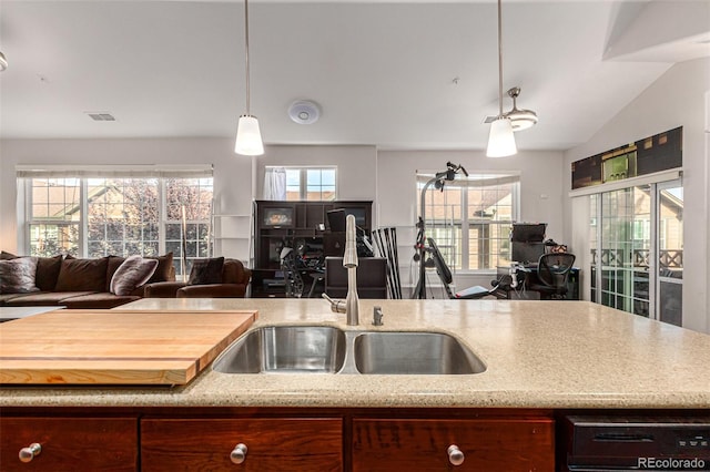 kitchen featuring light stone counters, sink, hanging light fixtures, and vaulted ceiling