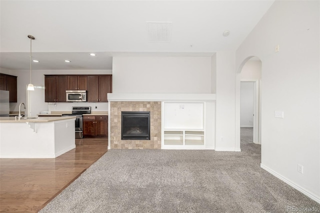 unfurnished living room featuring a tile fireplace, carpet, and sink