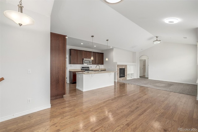 unfurnished living room with light hardwood / wood-style flooring, sink, vaulted ceiling, and a tile fireplace