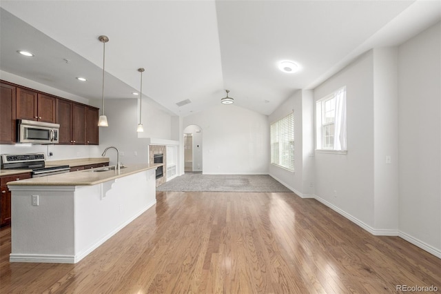 kitchen with appliances with stainless steel finishes, a center island with sink, hanging light fixtures, dark brown cabinetry, and sink