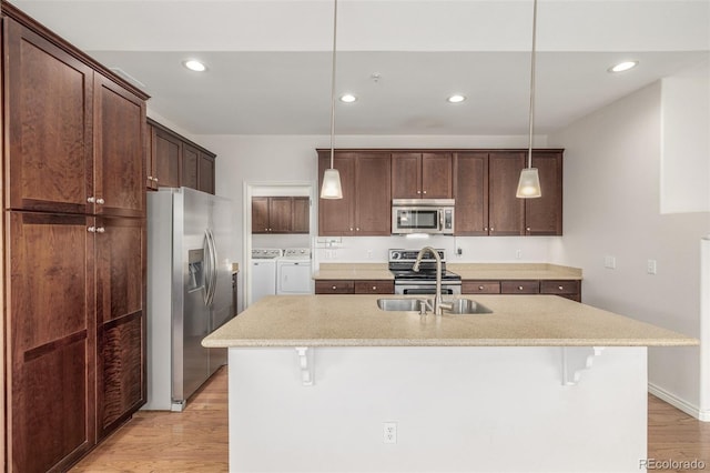 kitchen featuring washing machine and dryer, a kitchen bar, stainless steel appliances, and decorative light fixtures