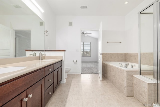 bathroom with tile patterned flooring, toilet, ceiling fan, vanity, and a relaxing tiled tub